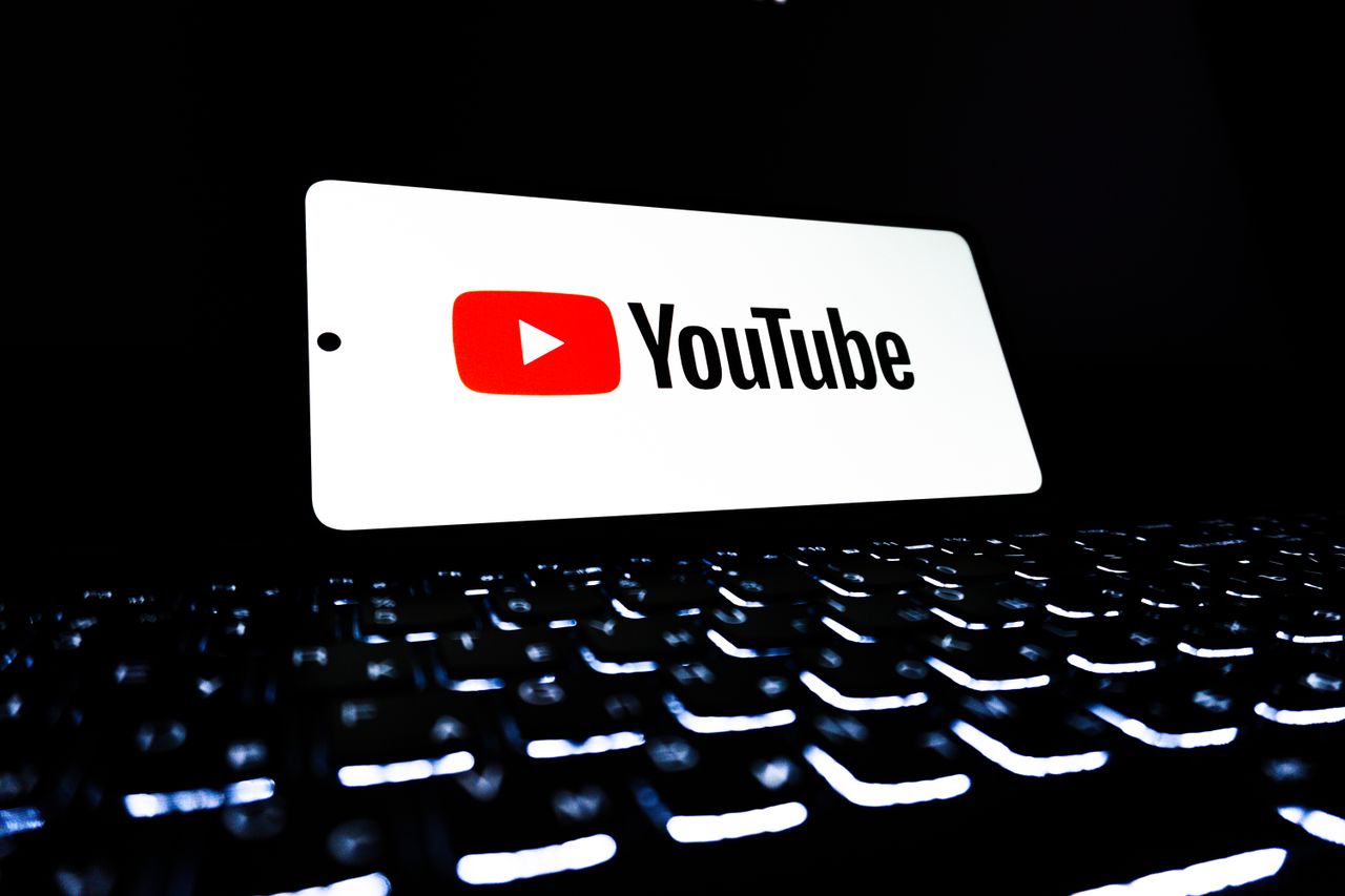 why-choose-us YouTube app icon displayed on a smartphone over an illuminated keyboard, representing digital media and online streaming.